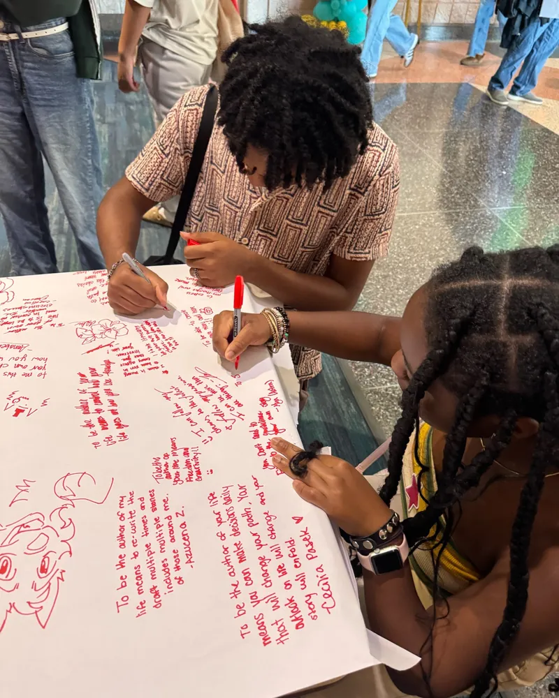 Students writing on the festival's giant banner