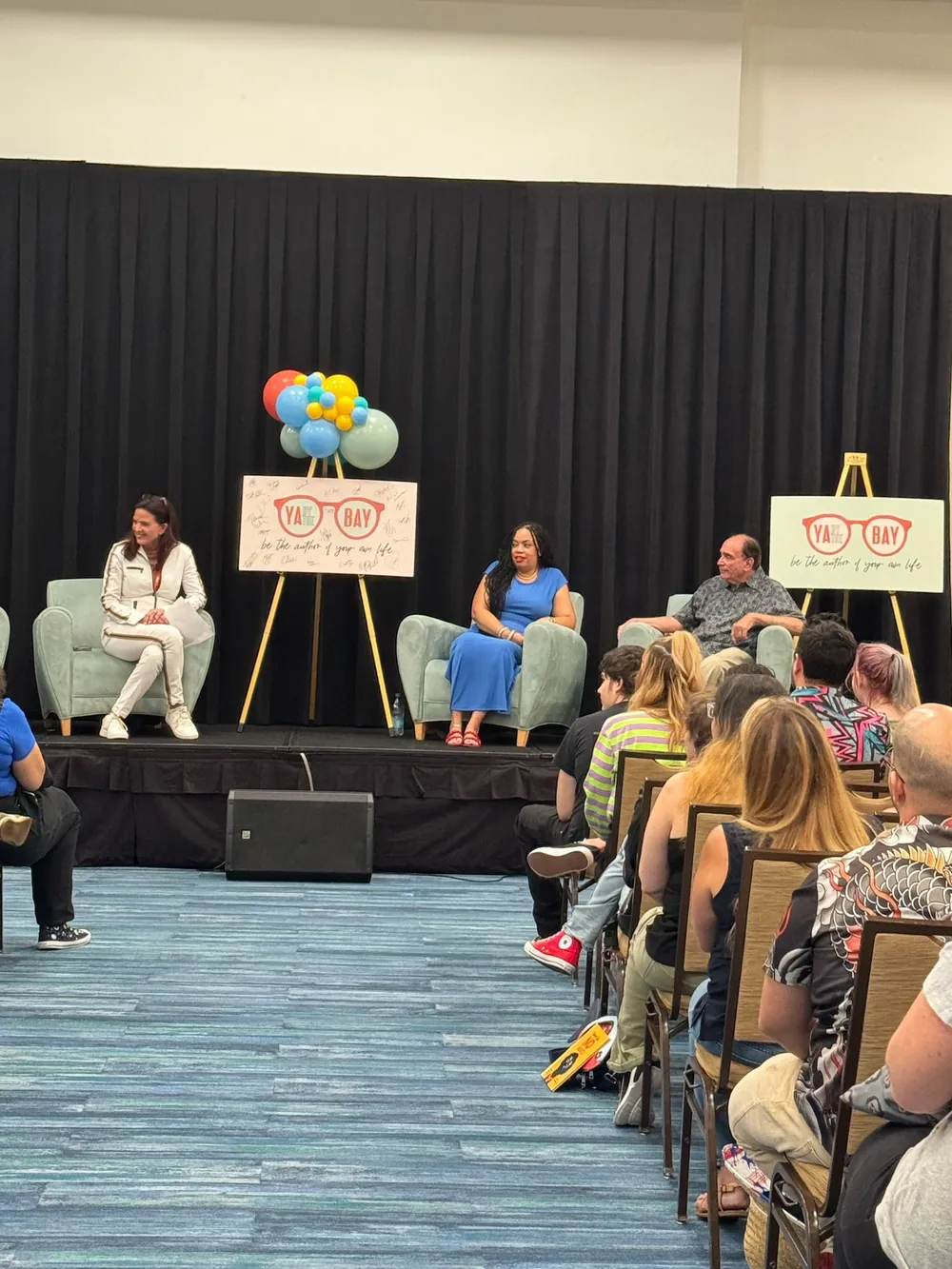 A full festival room watching a panel on stage