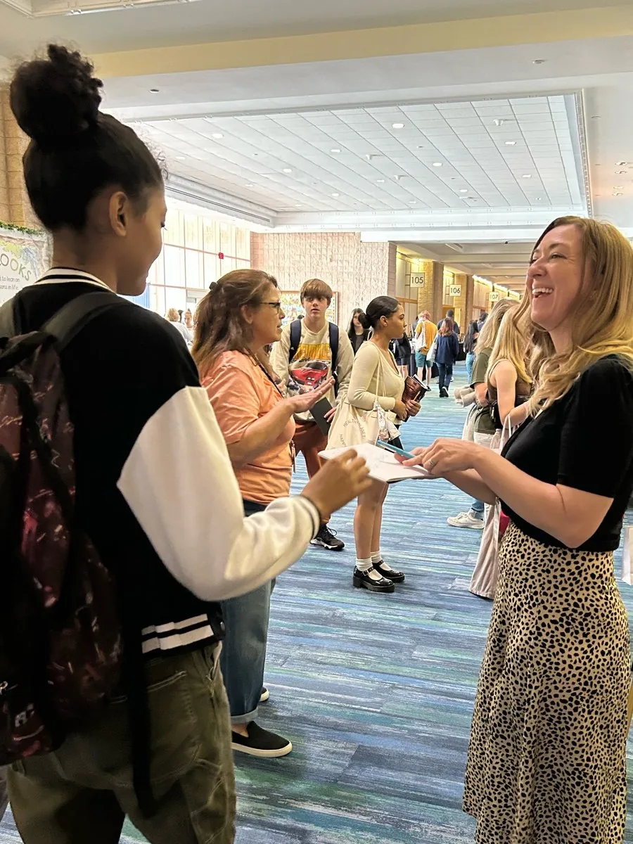 Author Kayla Tirrell laughing with two students in the festival hallway
