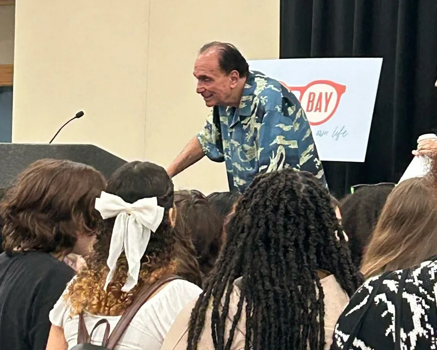 R.L. Stine leaning off the stage to greet students in the front rows