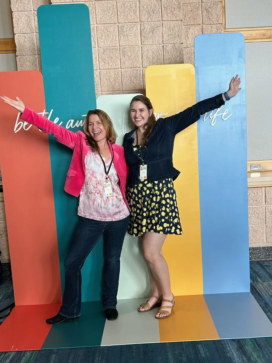 Festival guests with their arms up at the color backdrop