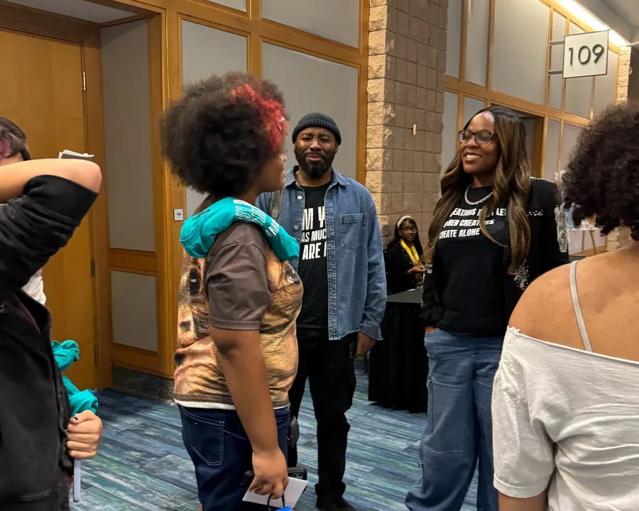 Author J'Nelle talking with a group of students in the hallway
