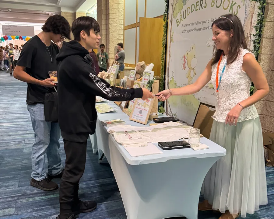 A student talking with Kristin at the Brudders Books table
